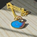 Blue Swan Pendant made with blue and red resin pigment in a golden frame