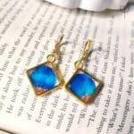 Close-up of Blue Whisper Drop Earrings showing blue petal details in resin