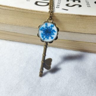 Blue Whisper Key pendant with blue pressed flower