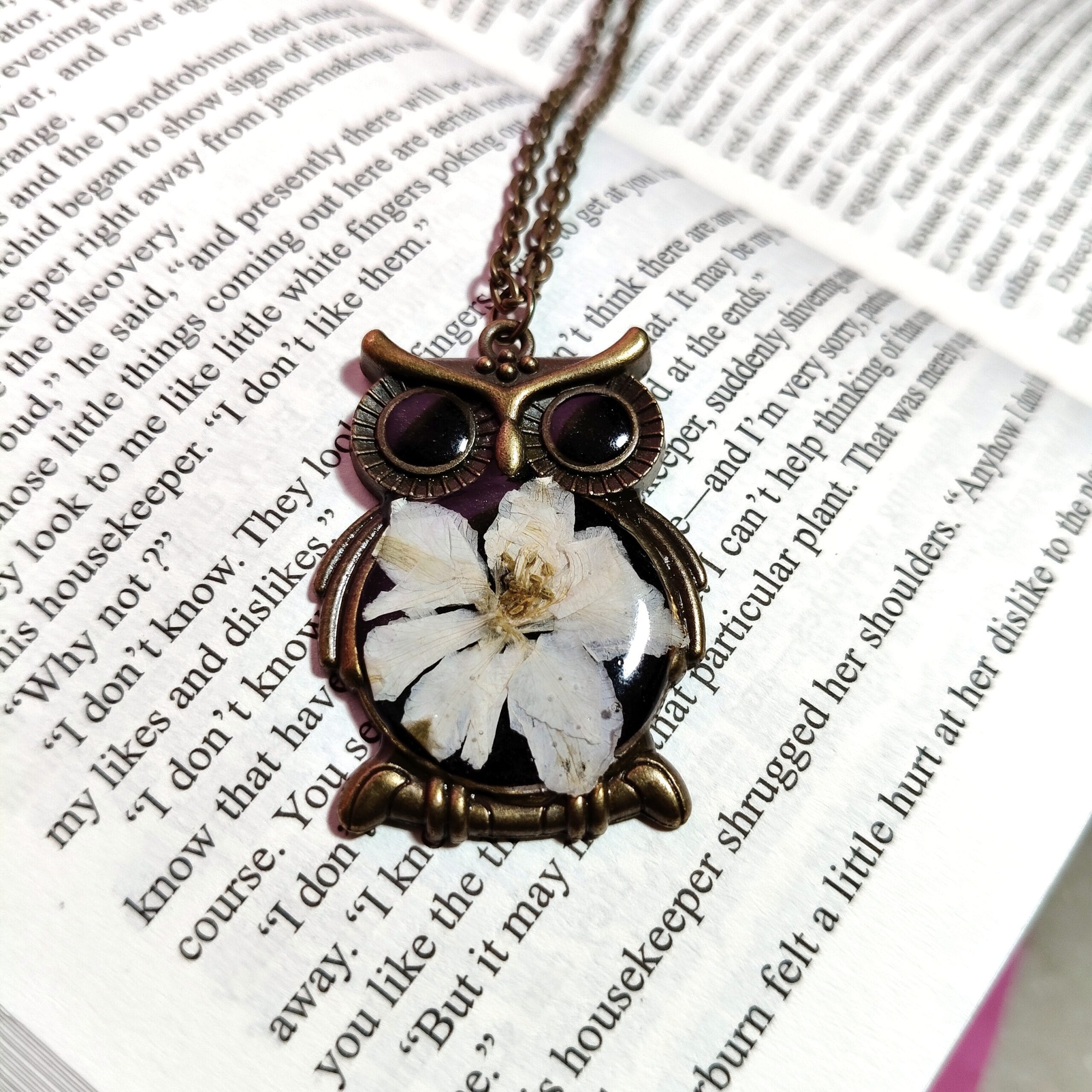 Close-up of handcrafted BotaniOwl pendant with pressed camellia
