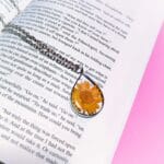 Dewbloom Pendant with real yellow daisy in teardrop resin frame