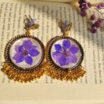Golden oxidised floral jhumka with soft purple camellia flower