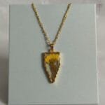 Gold arrow-shaped pendant with real dried daisy