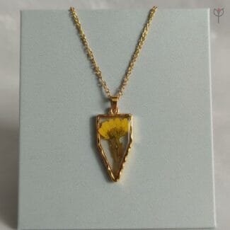 Gold arrow-shaped pendant with real dried daisy