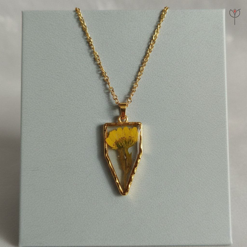 Gold arrow-shaped pendant with real dried daisy