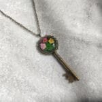 Plum Garden Key Pendant with preserved fern leaf and flower