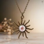 Antique Solstice Pendant featuring a pink plum flower in a bronze sunburst
