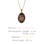 Close up of a botanical pendant on a delicate gold chain