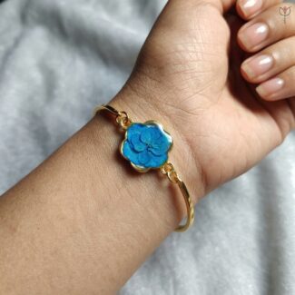 Handcrafted gold bangle featuring a real blue Hydrangea petal in resin