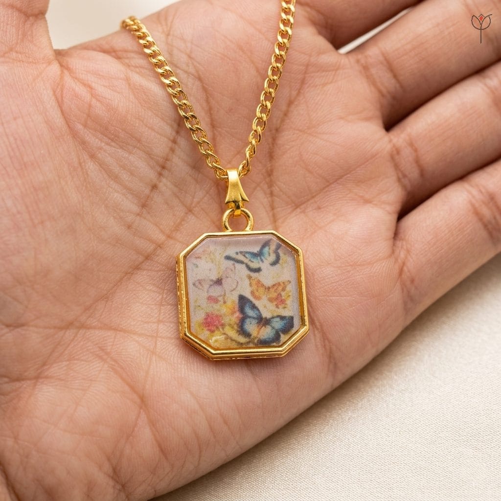 golden-butterfly-sketch-jewelry Handcrafted resin necklace featuring butterfly illustrations and a gold chain.