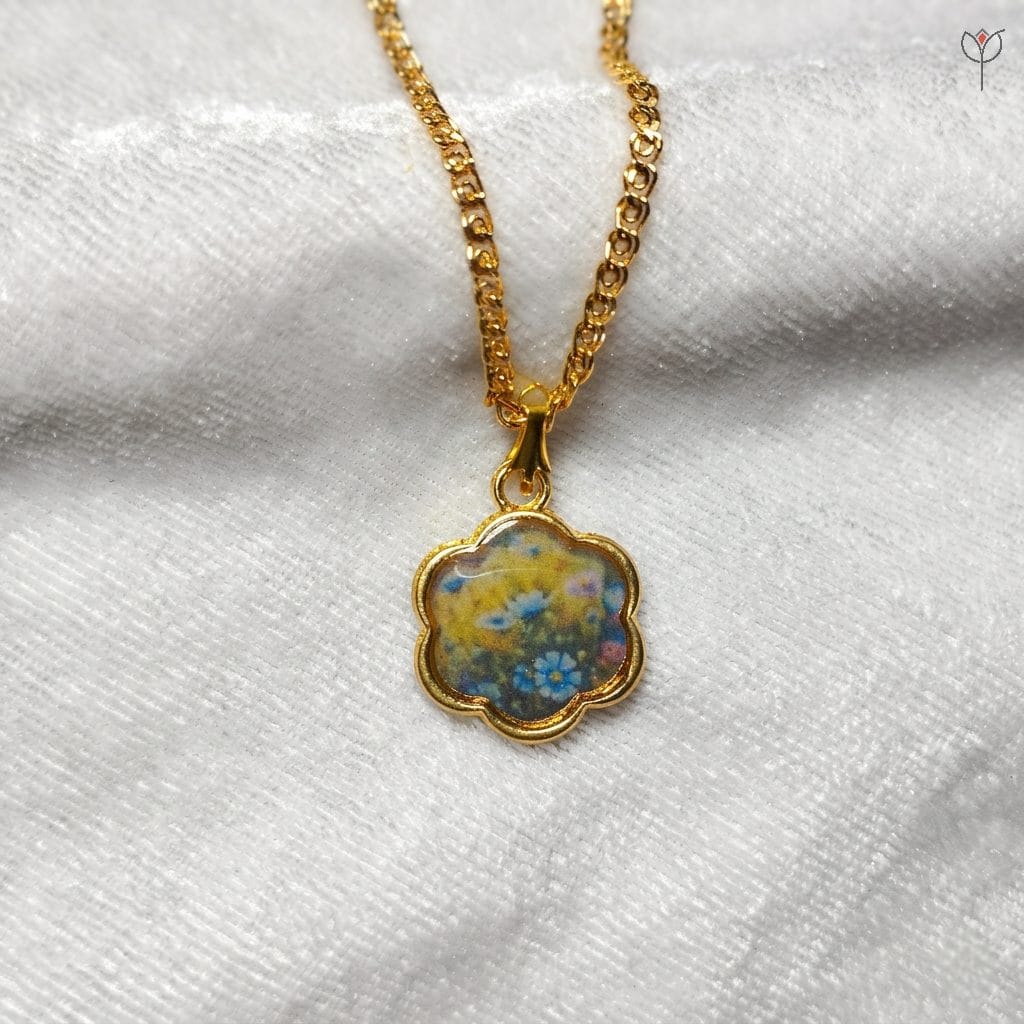 golden-meadow-art-jewelry Flower-shaped gold pendant with blue and yellow impressionist floral pigments