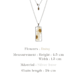 Close up of a botanical pendant on a sleek silver chain