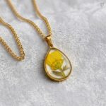 Sunny Aura Pendant with a yellow flower on a white background