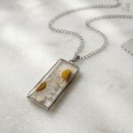 Two white daisies preserved in a silver rectangular base