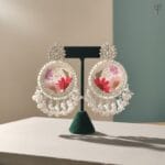 Moonlit Meadow Jhumka featuring real red daisies and green fern on an ivory white base