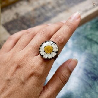 Model wearing the classic dark daisy resin ring on hand, showing adjustable band and preserved flower detail