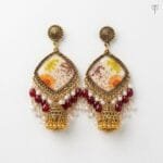 Close view of the pressed Queen Anne's lace and orange aster sealed in ivory resin at the centre of the Gilded Lace Meadow Resin Jhumka.