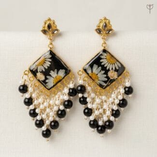 Onyx Daisy Jhumka with pressed white daisies and baby's breath set in black resin, framed in golden metal.