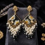 Close view of the pressed daisies and baby's breath sealed in black resin on the Onyx Daisy Jhumka.