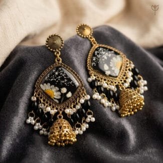 MystikFalls Midnight Garden Jhumkas close-up Preserved daisy and baby's breath set in black resin with ornate antique gold beaded border and pearl detailing