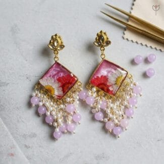 MystikFalls Rose Dew Jhumkas close-up Preserved daisy petals set in rose pink resin with kundan-style golden stud top and delicate pearl cluster detailing