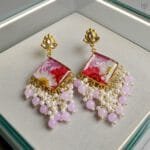 MystikFalls Rose Dew Jhumkas top-down view Pair of pressed daisy pink resin earrings