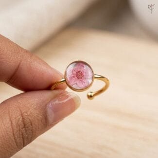 Close-up of dried pink plum blossom sealed in clear resin on the Cherry Spell Ring from Mystik Falls