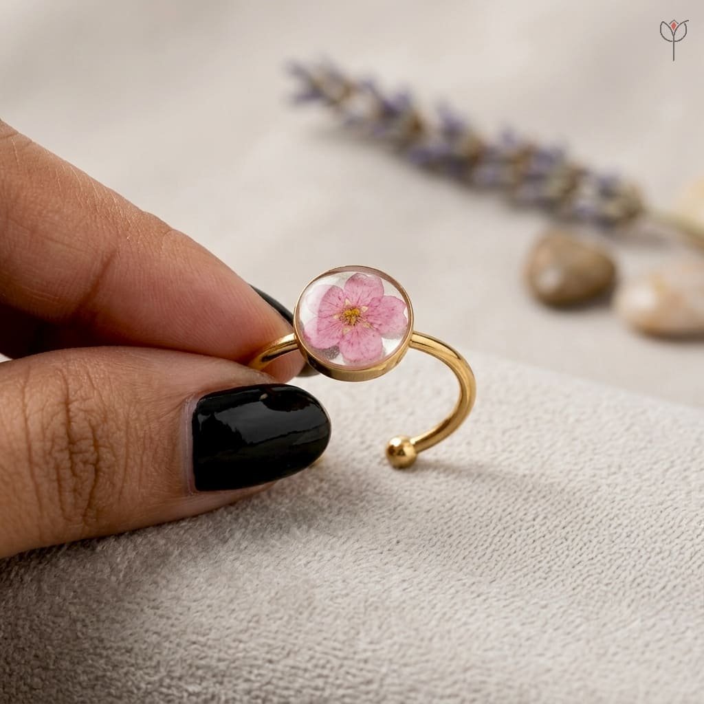 cherry-spell-ring-worn-on-hand-botanical-resin-jewellery Cherry Spell Ring worn on hand showing single pink plum flower in clear resin with adjustable golden band
