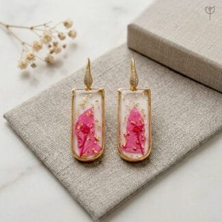 Liora Resin Earrings styled as handcrafted botanical drop jewellery with real preserved pink leaf in resin and gold-toned pavé ear hooks