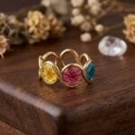 Mystic Trio Resin Ring worn on hand showing three colourful dried plum flowers in gold-tone setting