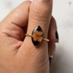 Close-up of dried plum blossom sealed in black resin on the Obsidian Bloom Ring from Mystik Falls