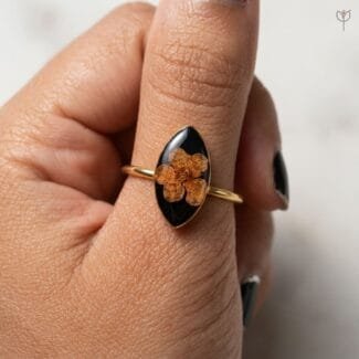 Close-up of dried plum blossom sealed in black resin on the Obsidian Bloom Ring from Mystik Falls