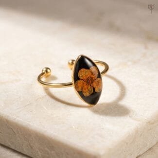 Obsidian Bloom Ring with dried orange plum flower set in black resin marquise shape with gold open band by Mystik Falls