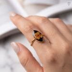 Obsidian Bloom Ring worn on hand showing dried plum flower in black resin with adjustable gold band