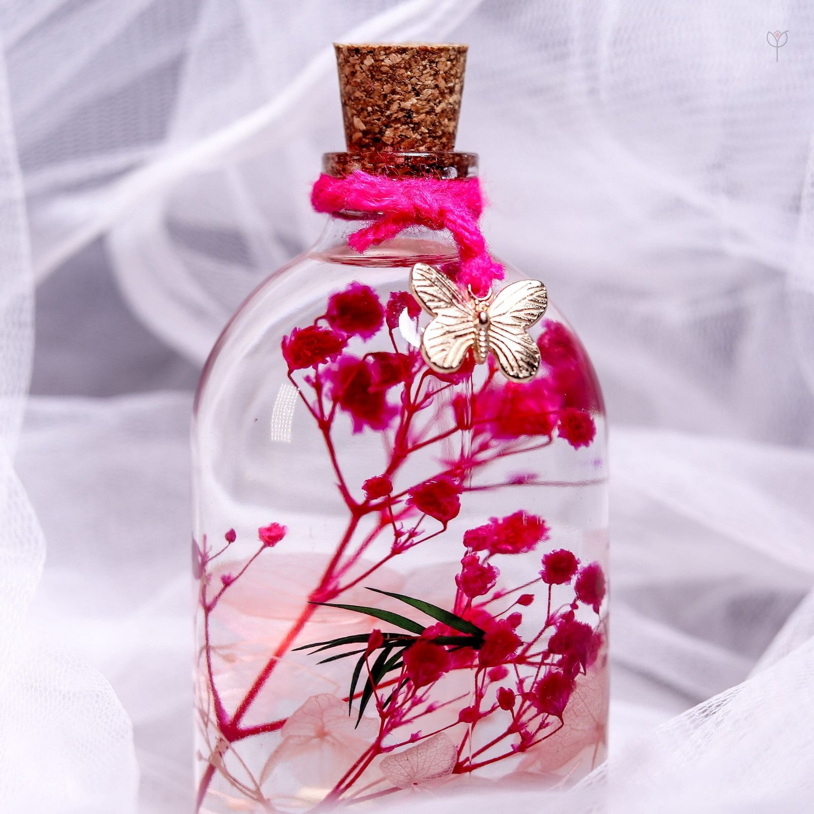 Close-up of real pink hydrangea and baby's breath preserved in mineral oil inside a cork glass bottle