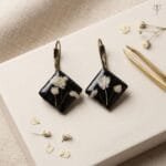 Vesper Resin Earrings styled as handcrafted botanical drop jewellery with real white flowers set in black resin and antique lever-back hooks